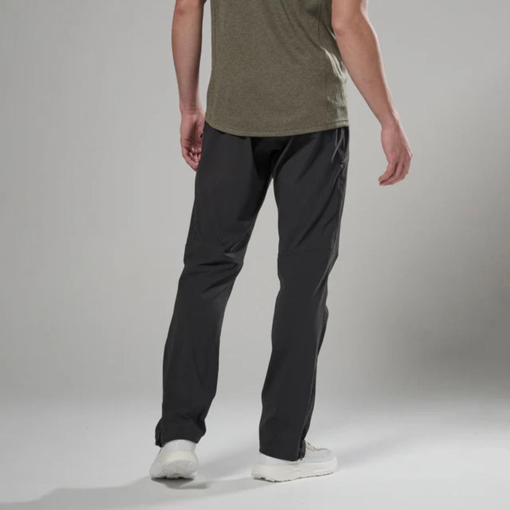 Back view of a person wearing an olive t-shirt and black jogger-style pants with elastic cuffs, paired with white sneakers.