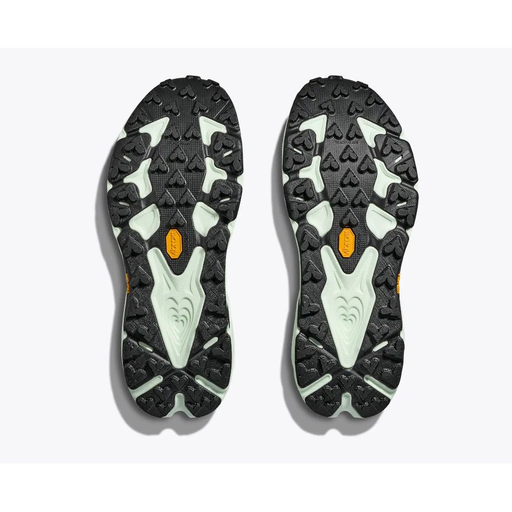 Pair of black trail running shoe soles viewed from below, with light green midsoles and orange Vibram logos on each foot side-by-side.
