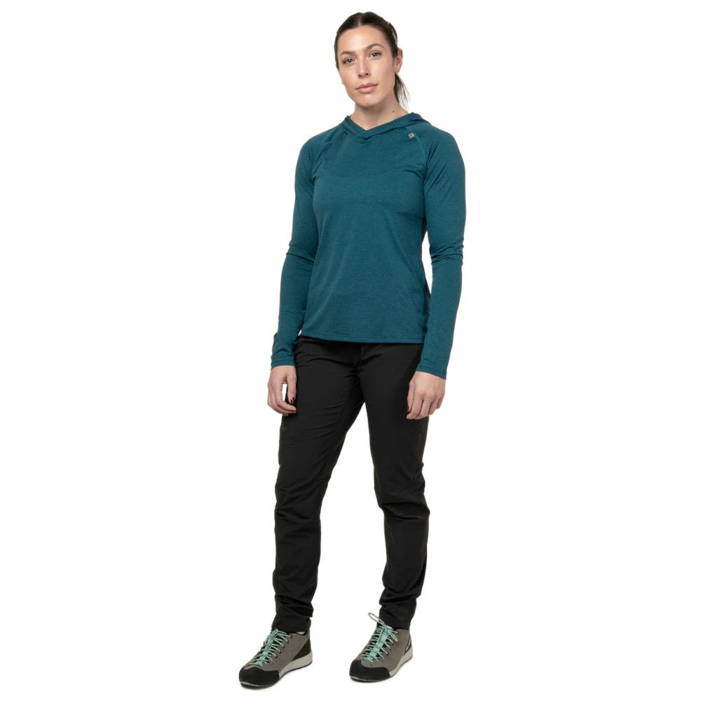 Woman modeling teal long-sleeve hoodie, black hiking pants, and green-laced hiking shoes.