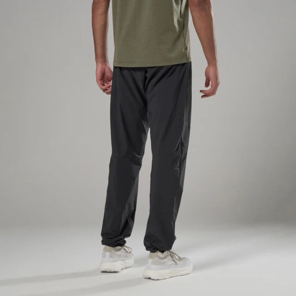 Back view of a person wearing an olive-green t-shirt, dark gray jogger pants, and white sneakers.