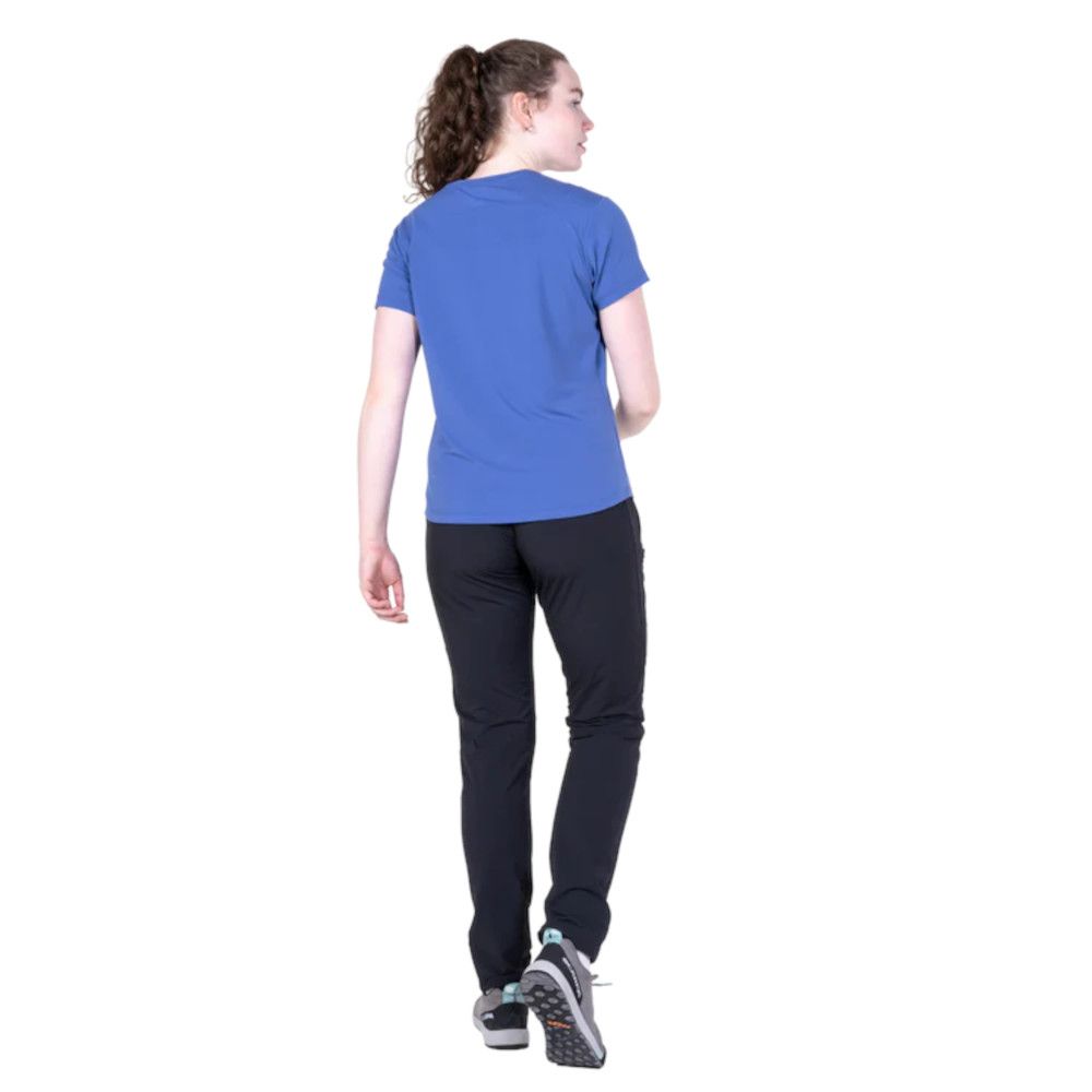 1_43c614ff-305c-487c-b528-744a22aa94cf Woman seen from behind wearing a blue short-sleeve shirt and dark athletic pants, mid-step, white sneakers with blue accents.