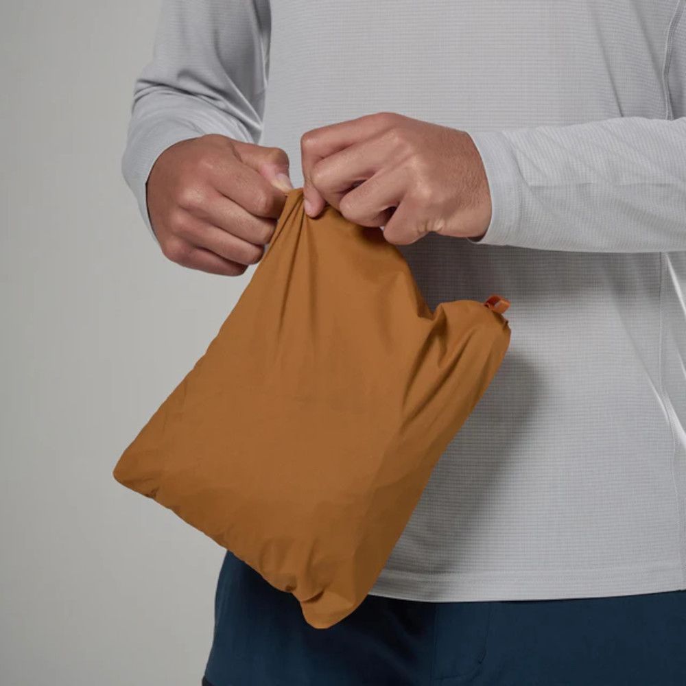 1_43c614ff-305c-487c-b528-744a22aa94cf Person holds a tan drawstring pouch with both hands against a light gray shirt.