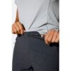 1_43c614ff-305c-487c-b528-744a22aa94cf Person cinching the adjustable waistband of dark athletic pants with a drawcord toggle.
