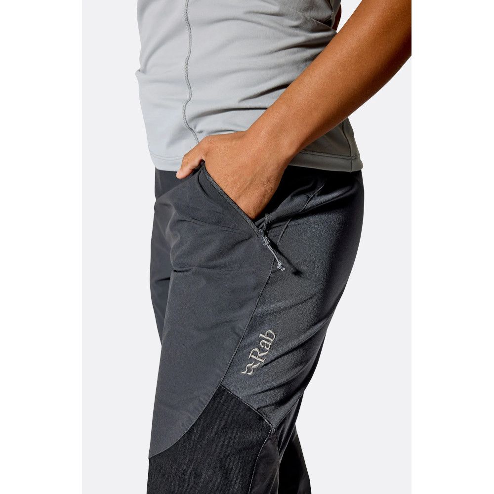 1_43c614ff-305c-487c-b528-744a22aa94cf Close-up of a person wearing gray athletic top and dark hiking pants with a zip pocket and Rab logo on the thigh