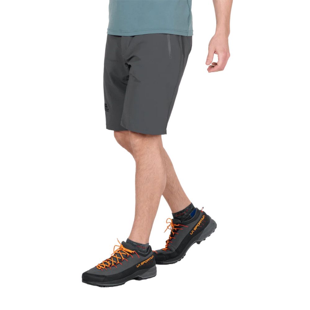 1_43c614ff-305c-487c-b528-744a22aa94cf Person wearing gray shorts stepping forward, showcasing black/orange La Sportiva hiking shoes with bright orange laces