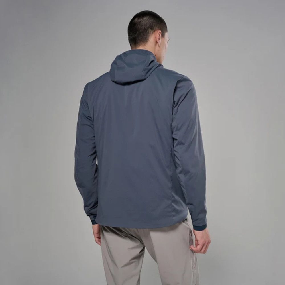Man wearing a blue hooded jacket, viewed from the back, with beige pants against a gray background