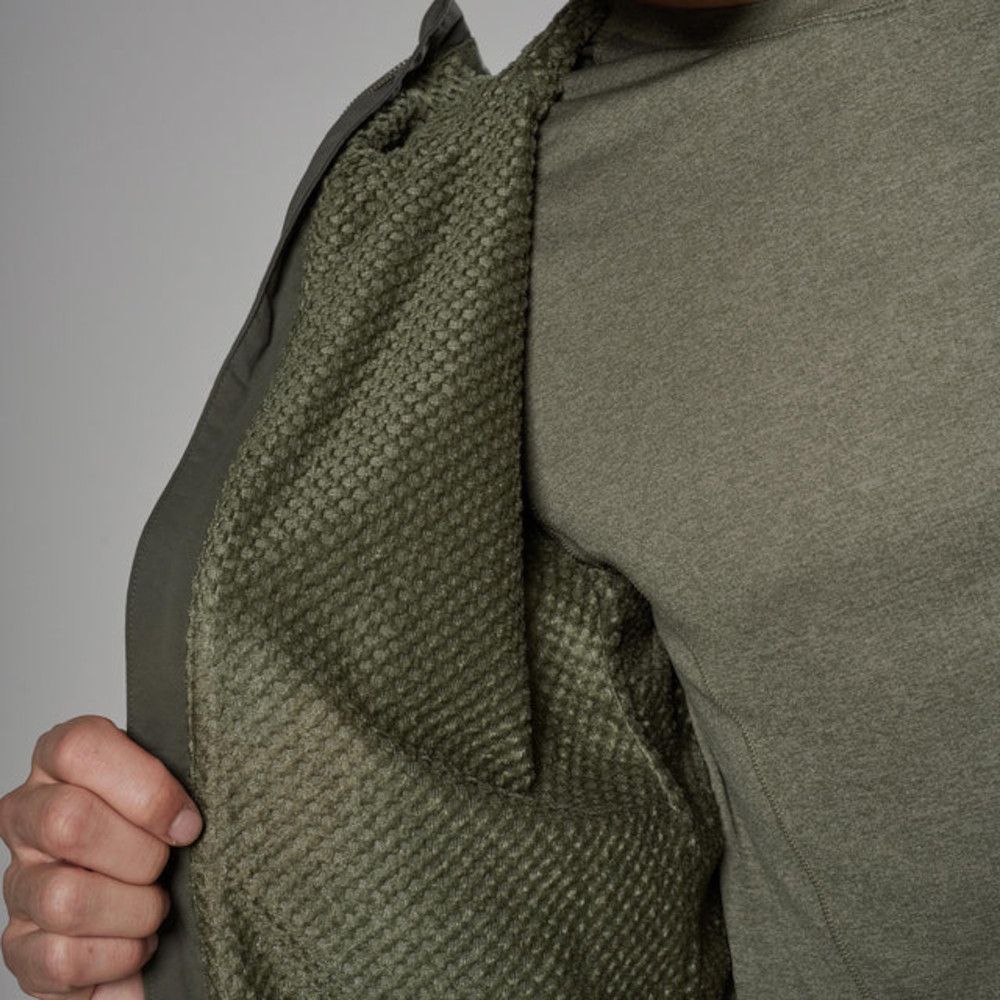 Close-up of a person opening a green jacket to reveal a soft, textured olive lining.