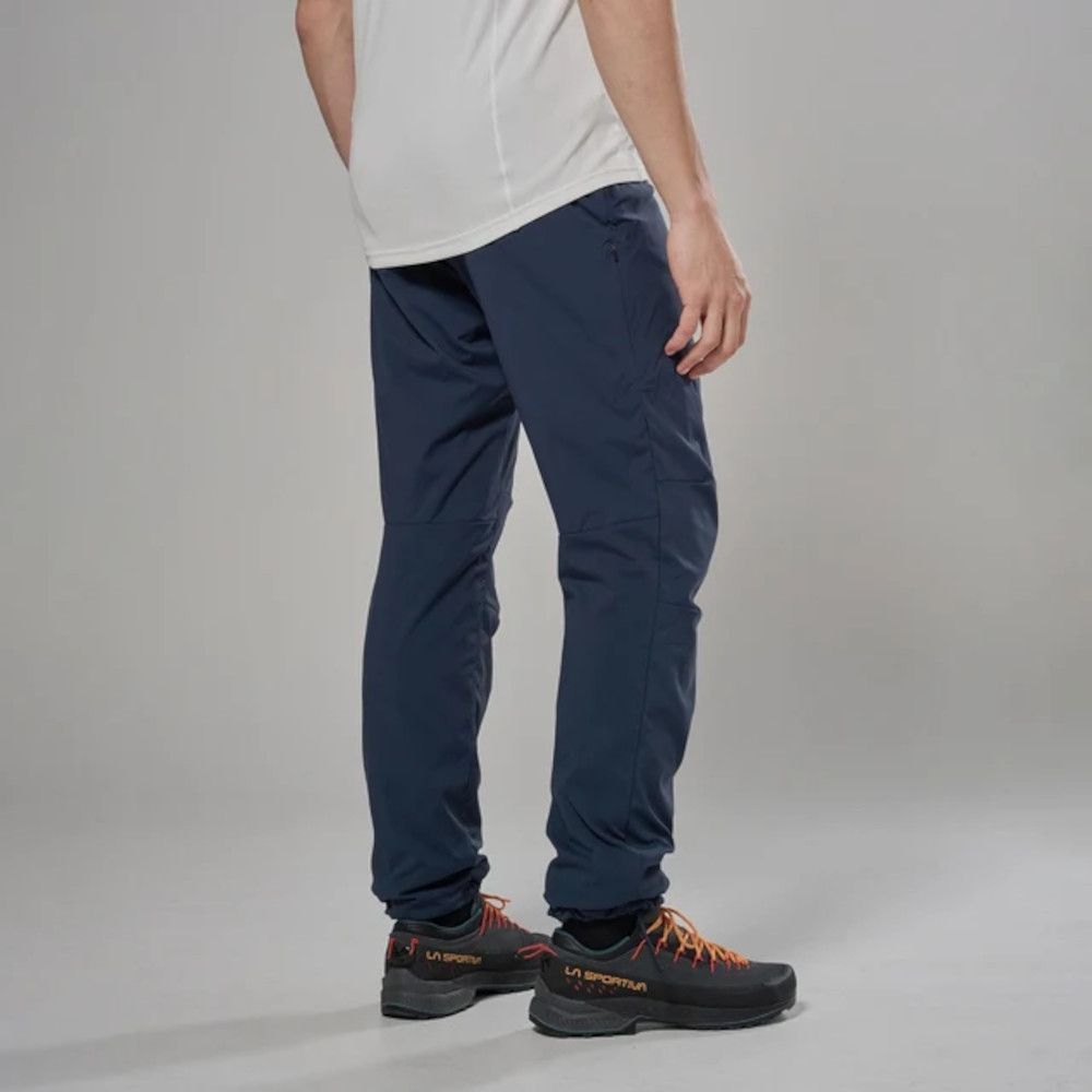 Side view of a person wearing navy hiking pants with elastic cuffs and orange-laced La Sportiva trail shoes.