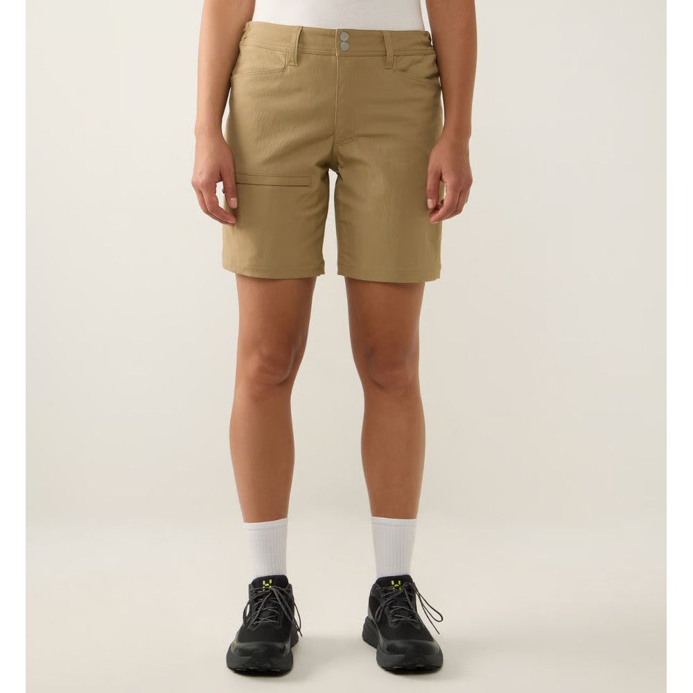 Front view of a person in khaki shorts, a white top, white socks, and black sneakers.