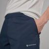 Close-up of a person wearing navy Montane hiking pants with a zippered side pocket and hand in pocket lashing the waistband edge visible