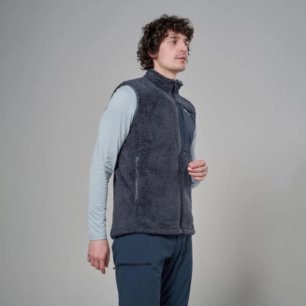 MKLPR_ECL_P_1_square_b214d799-76b2-4a64-a0ae-a2325d30818b_640x Side view of a man wearing a dark gray fleece vest over a light blue long-sleeve shirt, standing indoors.