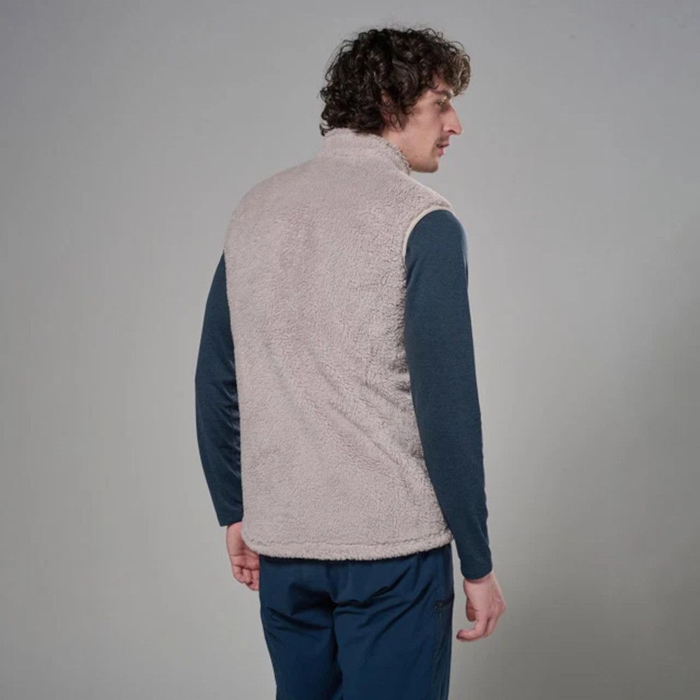 MKLPR_ECL_P_1_square_b214d799-76b2-4a64-a0ae-a2325d30818b_640x Man with curly hair seen from behind, wearing a beige sherpa vest over a navy long-sleeve shirt and blue pants.